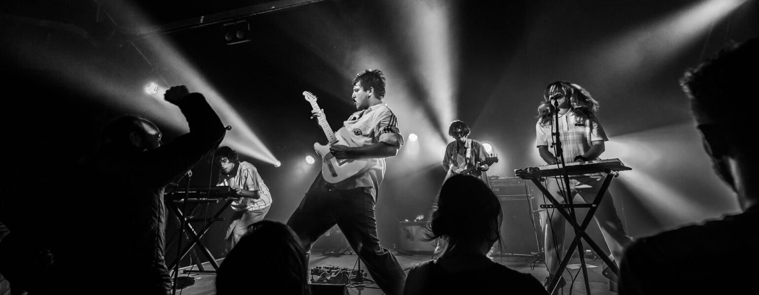Concert de rock avec éclairage intense et musiciens.