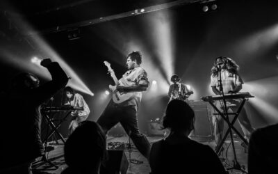 Concert de rock avec éclairage intense et musiciens.