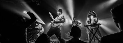 Concert de rock avec éclairage intense et musiciens.