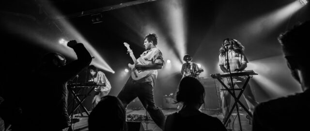 Concert de rock avec éclairage intense et musiciens.