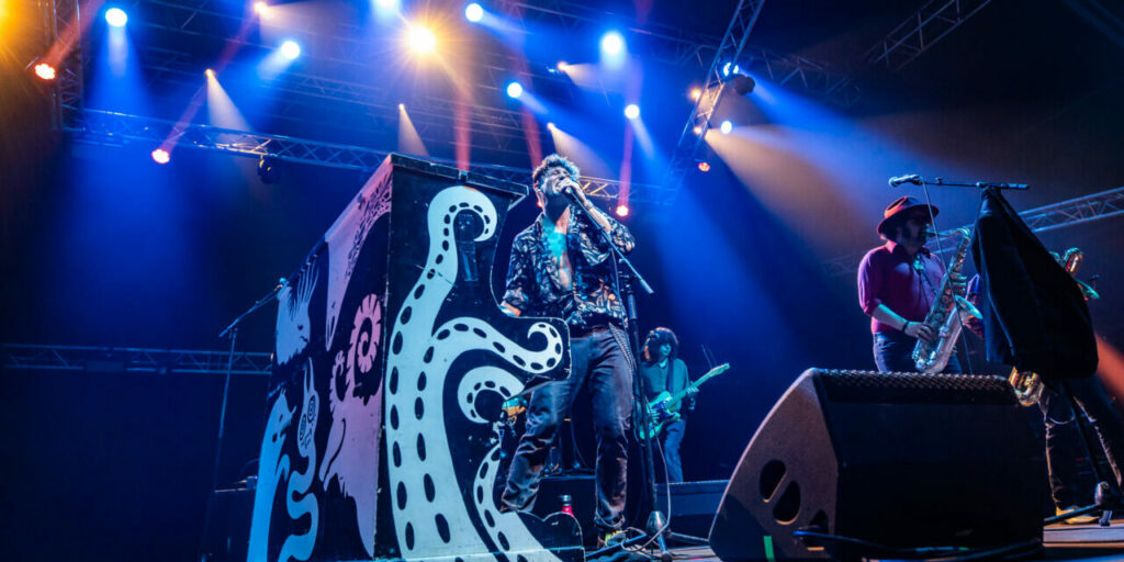 Groupe jouant en concert avec éclairage vibrant.