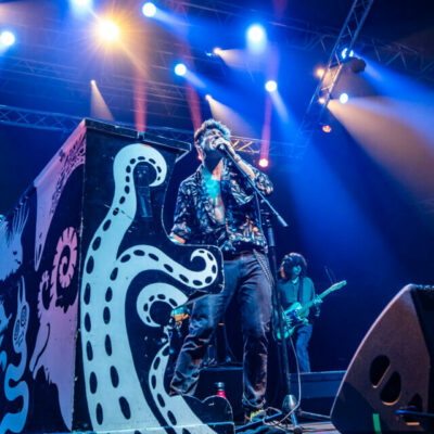 Groupe jouant en concert avec éclairage vibrant.