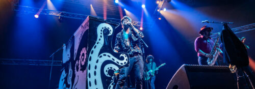 Groupe jouant en concert avec éclairage vibrant.