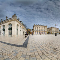 Place pavée avec bâtiments historiques sous ciel nuageux.