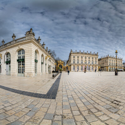 Place pavée avec bâtiments historiques sous ciel nuageux.