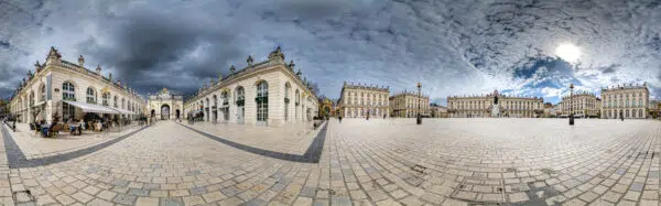 Place pavée avec bâtiments historiques sous ciel nuageux.