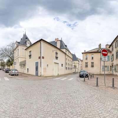 Rue pavée avec bâtiments historiques, ciel nuageux