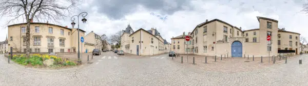 Rue pavée avec bâtiments historiques, ciel nuageux