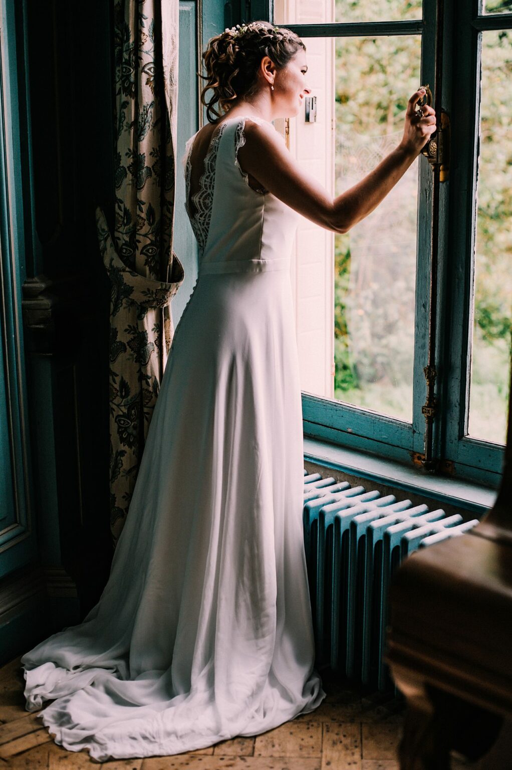 Femme en robe de mariée regardant par la fenêtre.