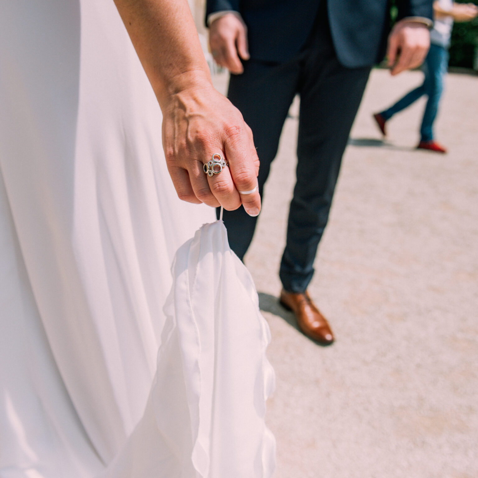 Main tenant une robe blanche, homme en costume.