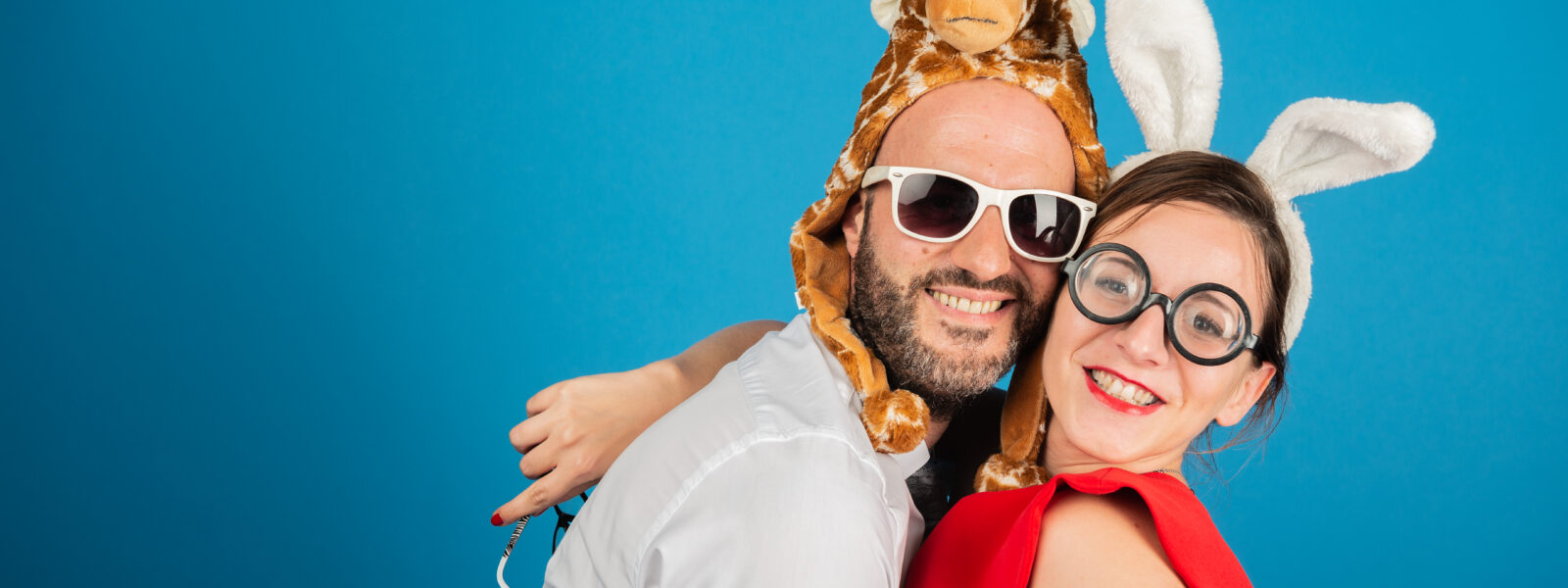 Deux personnes déguisées souriant devant un fond bleu.