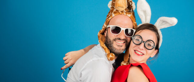 Deux personnes déguisées souriant devant un fond bleu.