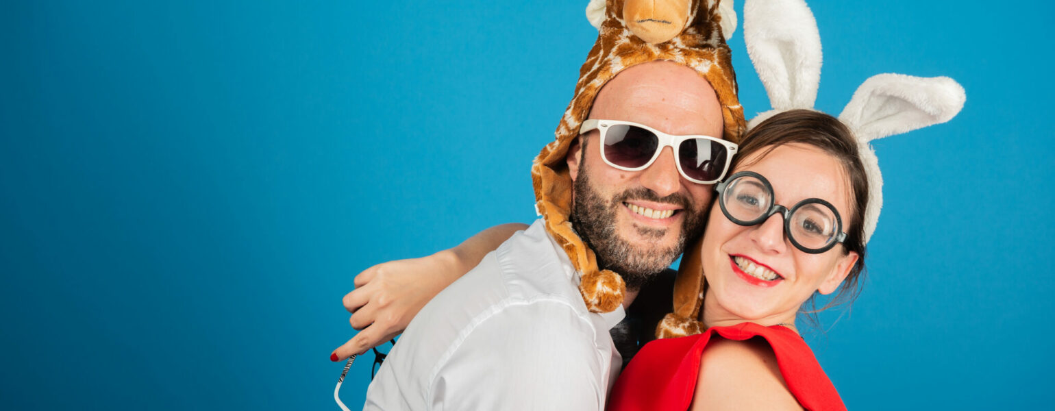 Deux personnes déguisées souriant devant un fond bleu.