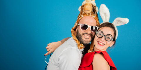 Deux personnes déguisées souriant devant un fond bleu.