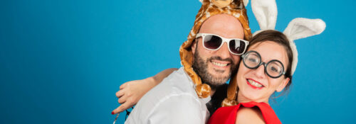 Deux personnes déguisées souriant devant un fond bleu.
