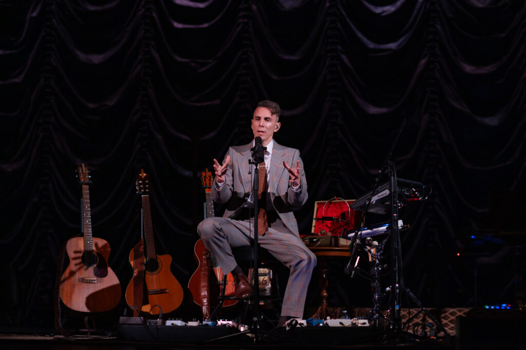 Musicien sur scène avec guitares et équipement.