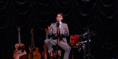 Musicien sur scène avec guitares et équipement.