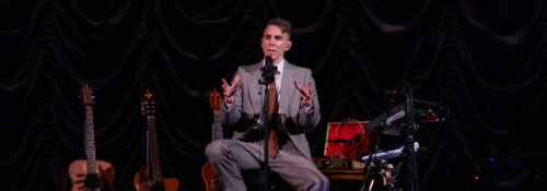 Musicien sur scène avec guitares et équipement.