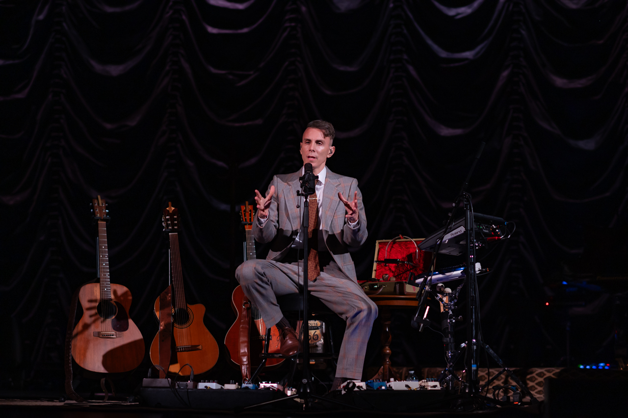 Musicien sur scène avec guitares et équipement.