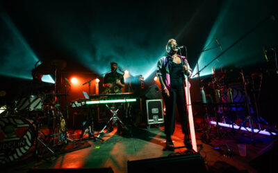 Concert en live avec chanteur et musiciens sur scène.