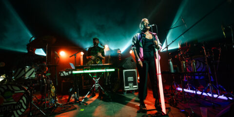 Concert en live avec chanteur et musiciens sur scène.