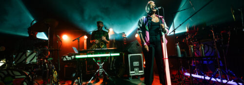 Concert en live avec chanteur et musiciens sur scène.