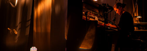 Musicienne jouant du piano sur scène éclairée.