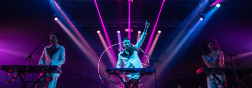 Concert avec lumières violettes et artistes sur scène.