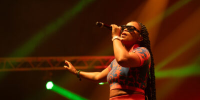 Chanteuse en concert avec micro et lunettes.