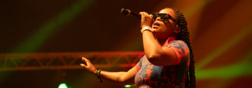 Chanteuse en concert avec micro et lunettes.