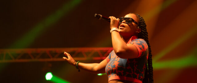 Chanteuse en concert avec micro et lunettes.