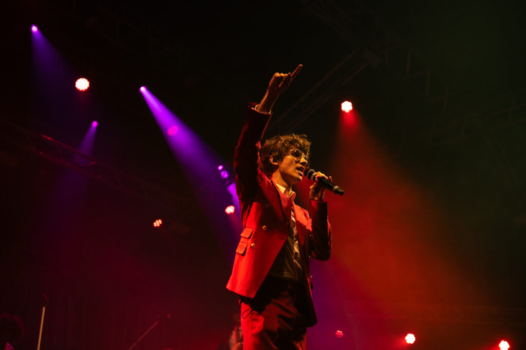 Chanteur sur scène avec micro et lumières colorées.