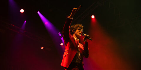 Chanteur sur scène avec micro et lumières colorées.