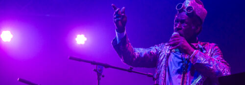 Musicien jouant du saxophone sur scène violet éclairée.