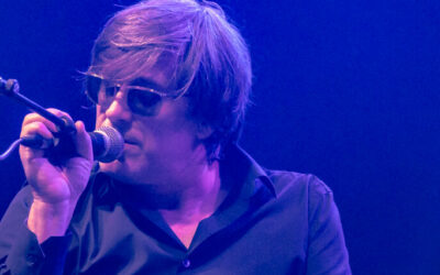 Chanteur sur scène avec lunettes de soleil.