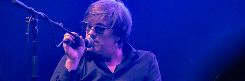 Chanteur sur scène avec lunettes de soleil.