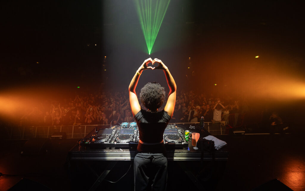 DJ sur scène devant foule enthousiaste.