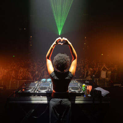 DJ sur scène devant foule enthousiaste.