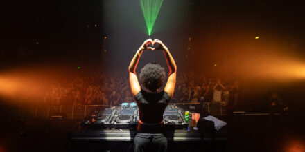 DJ sur scène devant foule enthousiaste.