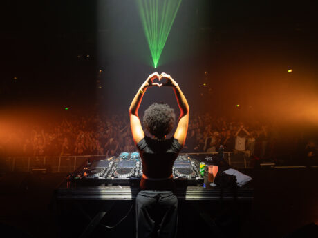 DJ sur scène devant foule enthousiaste.