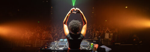 DJ sur scène devant foule enthousiaste.