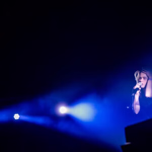 Chanteur sur scène avec lumière bleue intense.