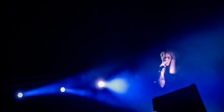 Chanteur sur scène avec lumière bleue intense.