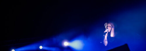 Chanteur sur scène avec lumière bleue intense.