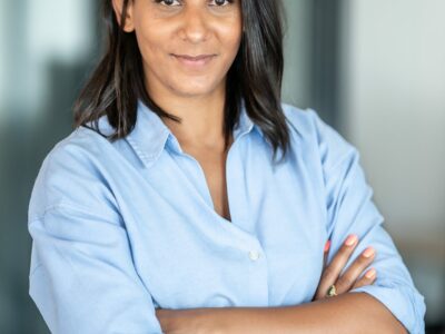 Femme souriante bras croisés en chemise bleue.