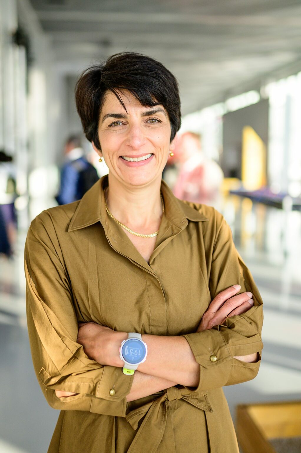 Femme souriante bras croisés en intérieur lumineux.