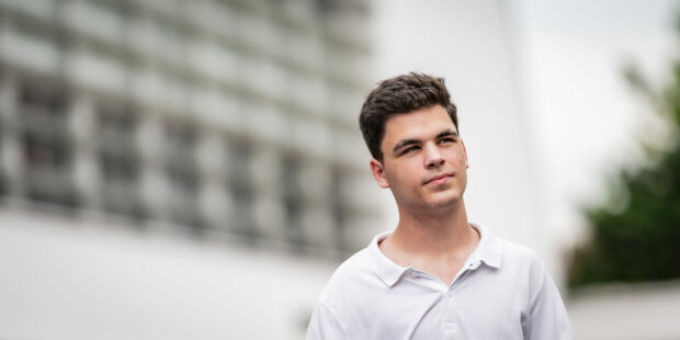 Jeune homme pensif en extérieur urbain flou.