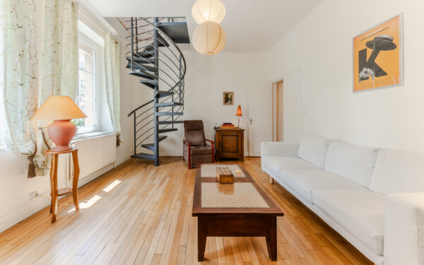 Salon avec escalier en colimaçon et canapé blanc.