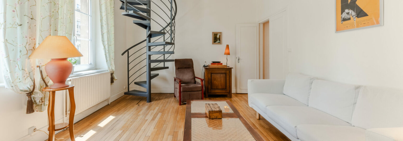 Salon avec escalier en colimaçon et canapé blanc.