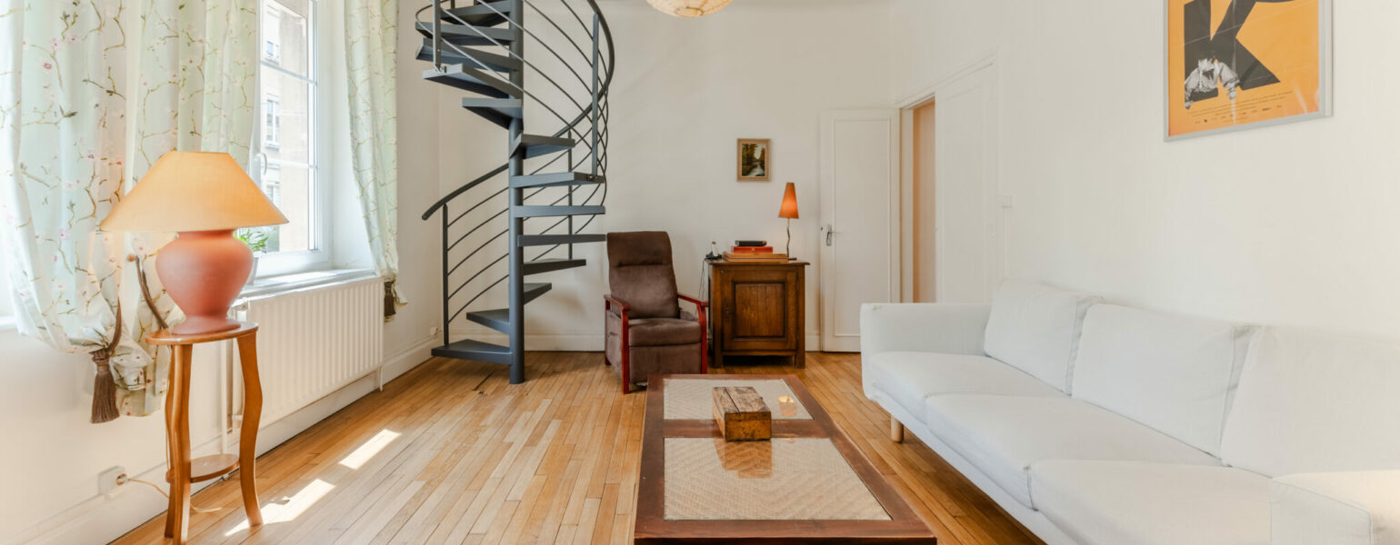 Salon avec escalier en colimaçon et canapé blanc.